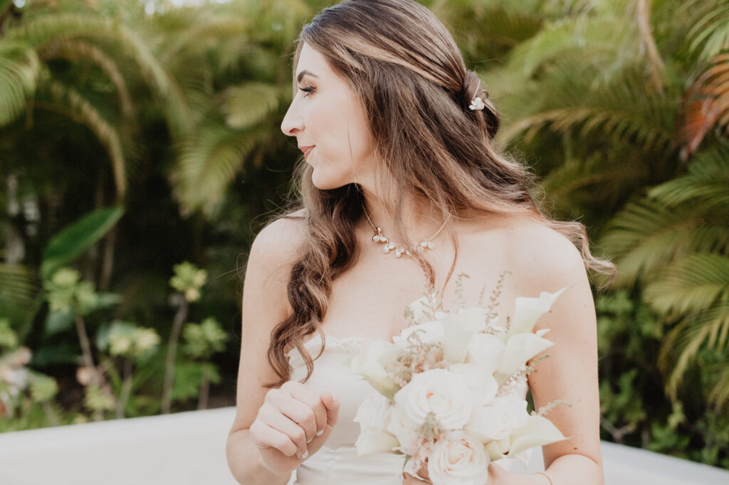 Bride holding white bouquet at St Regis Punta Mita elopement, lush tropical greenery backdrop