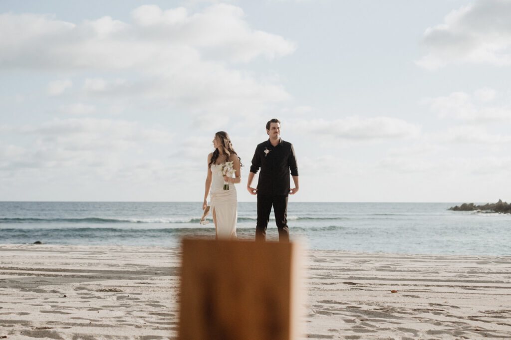 Elopement couple on beach at St Regis Punta Mita, bride in white gown holding bouquet, ocean backdrop