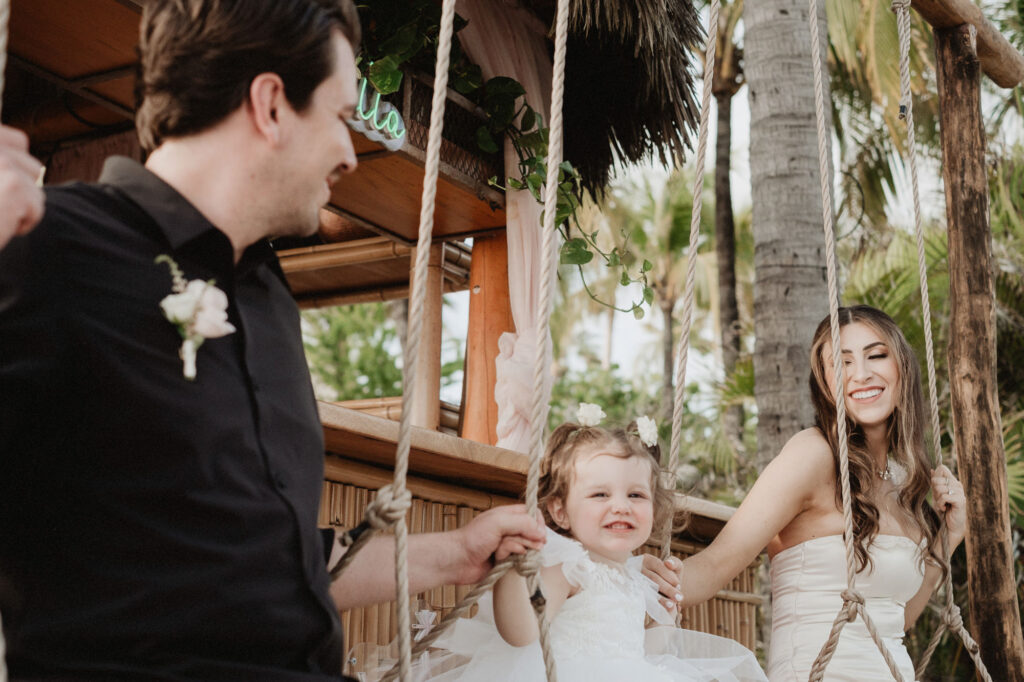 Bride and groom with flower girl on rope swing at St Regis Punta Mita elopement wedding