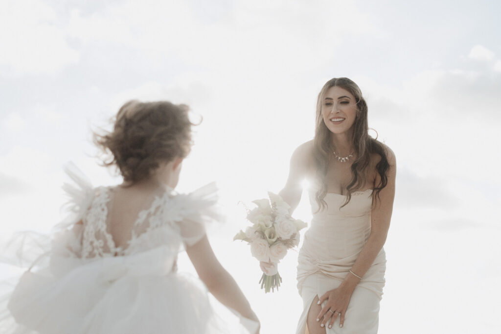 Bride laughing as flower girl runs to her during elopement at St Regis Punta Mita, Mexico