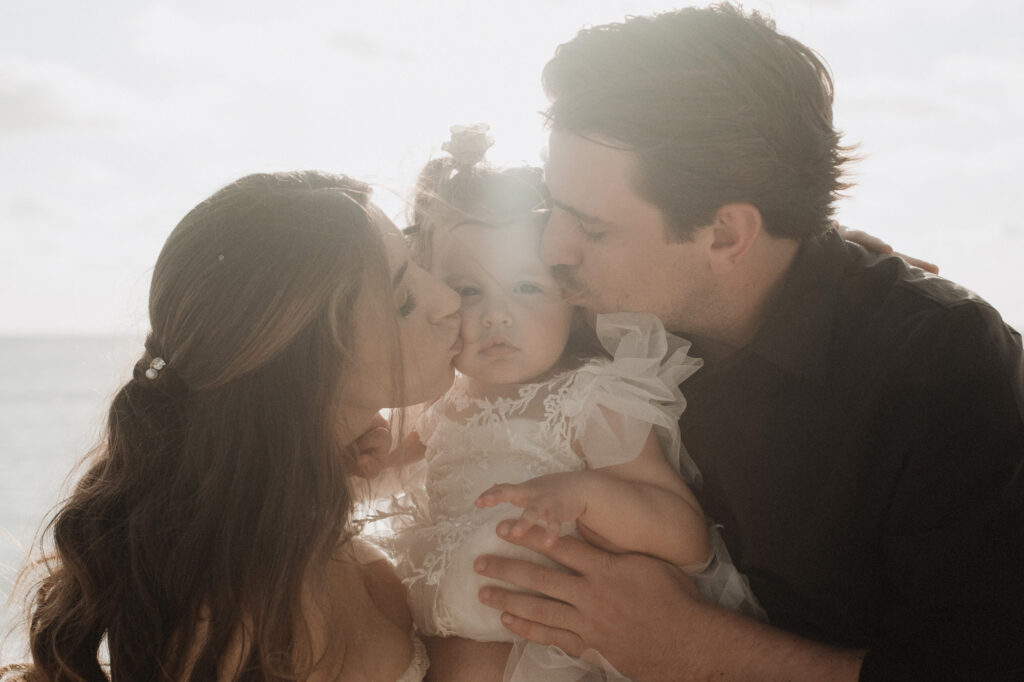 Parents kissing baby girl on the cheek during elopement session at St Regis Punta Mita, Mexico