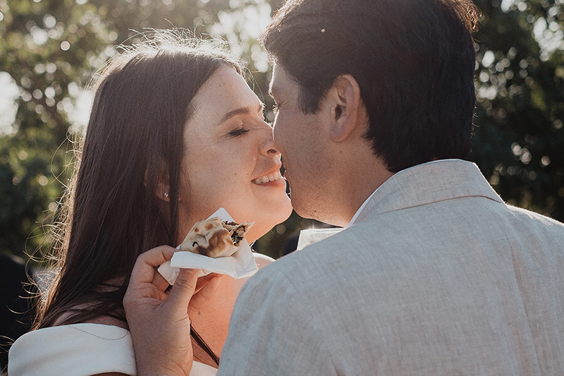 Couple sharing a sweet moment with a s'more during their Tulum wedding reception, golden hour light