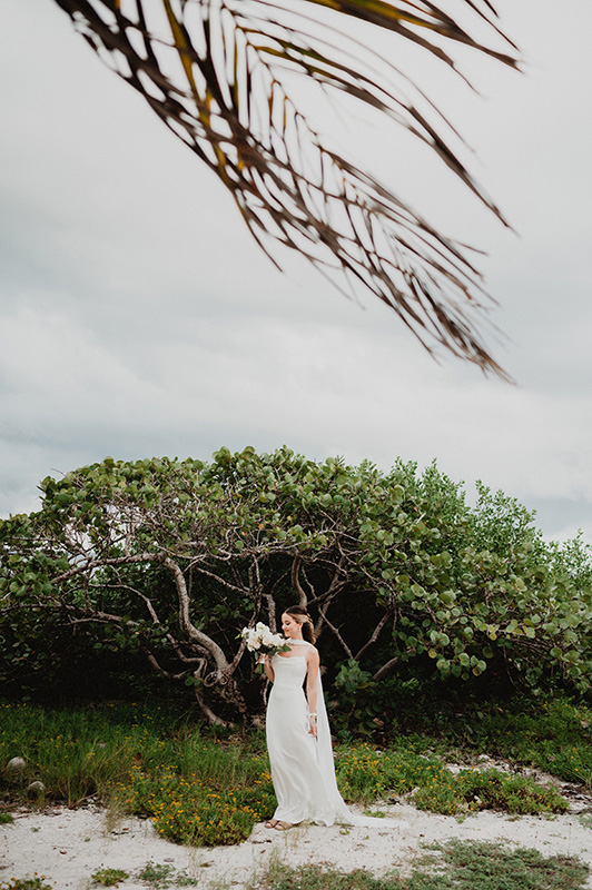 Bride in white gown holding bouquet at Blue Venado beach, Paamul wedding ceremony, documentary film photography