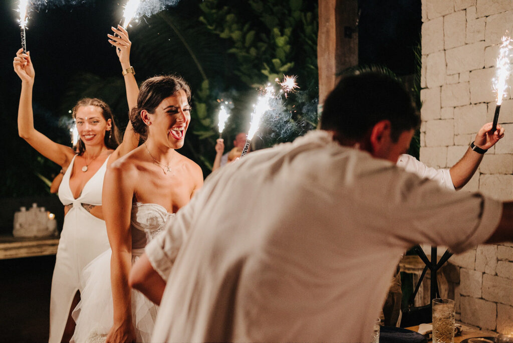 Bride laughing with sparklers at Papaya Playa Project Tulum wedding reception at night
