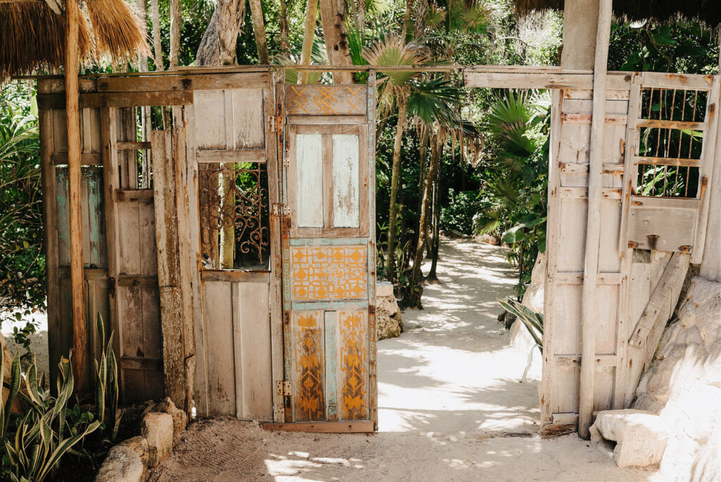 Rustic painted wooden doors at Papaya Playa Project, Tulum wedding venue entrance surrounded by jungle