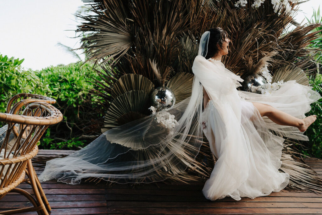 Bride in flowing white gown and veil dancing at Papaya Playa Project Tulum wedding ceremony on wooden deck