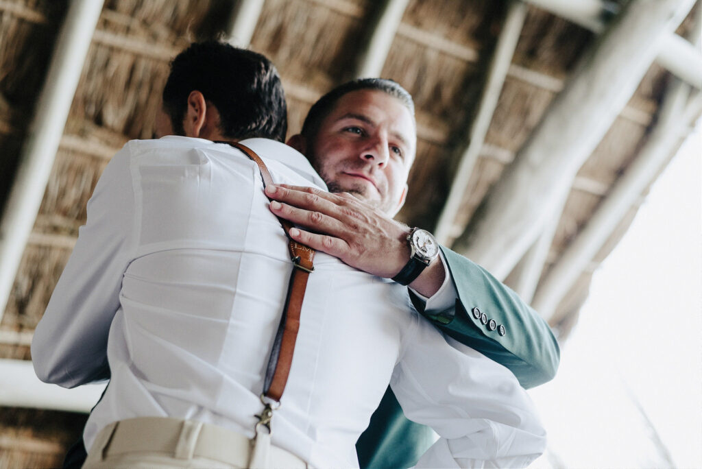Two grooms sharing an emotional embrace at Papaya Playa Project Tulum wedding ceremony