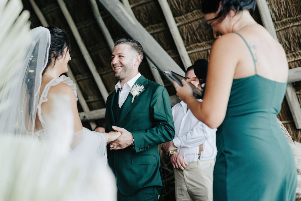 Groom in emerald suit laughing during wedding ceremony at Papaya Playa Project, Tulum