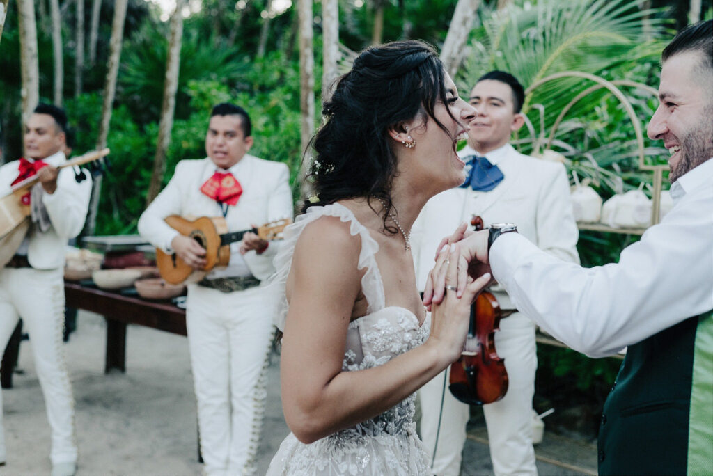 Bride laughing with groom during mariachi performance at Papaya Playa Project wedding reception, Tulum