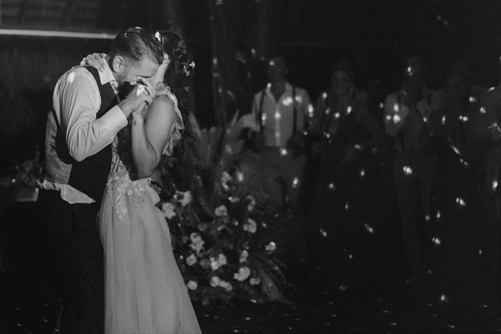 Bride and groom share emotional first dance at Papaya Playa Project Tulum wedding reception, guests holding lights