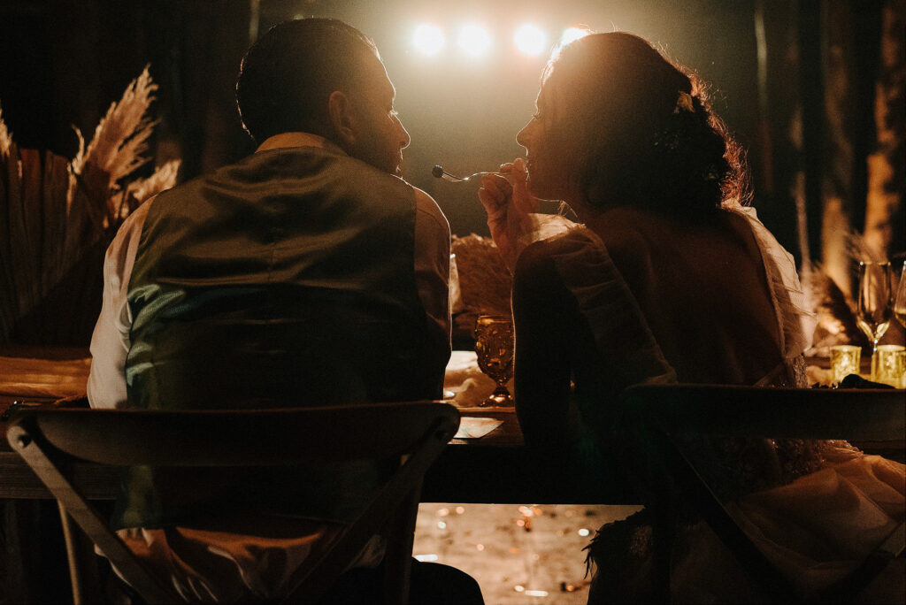 Bride and groom sharing a fork at candlelit wedding reception, Papaya Playa Project Tulum